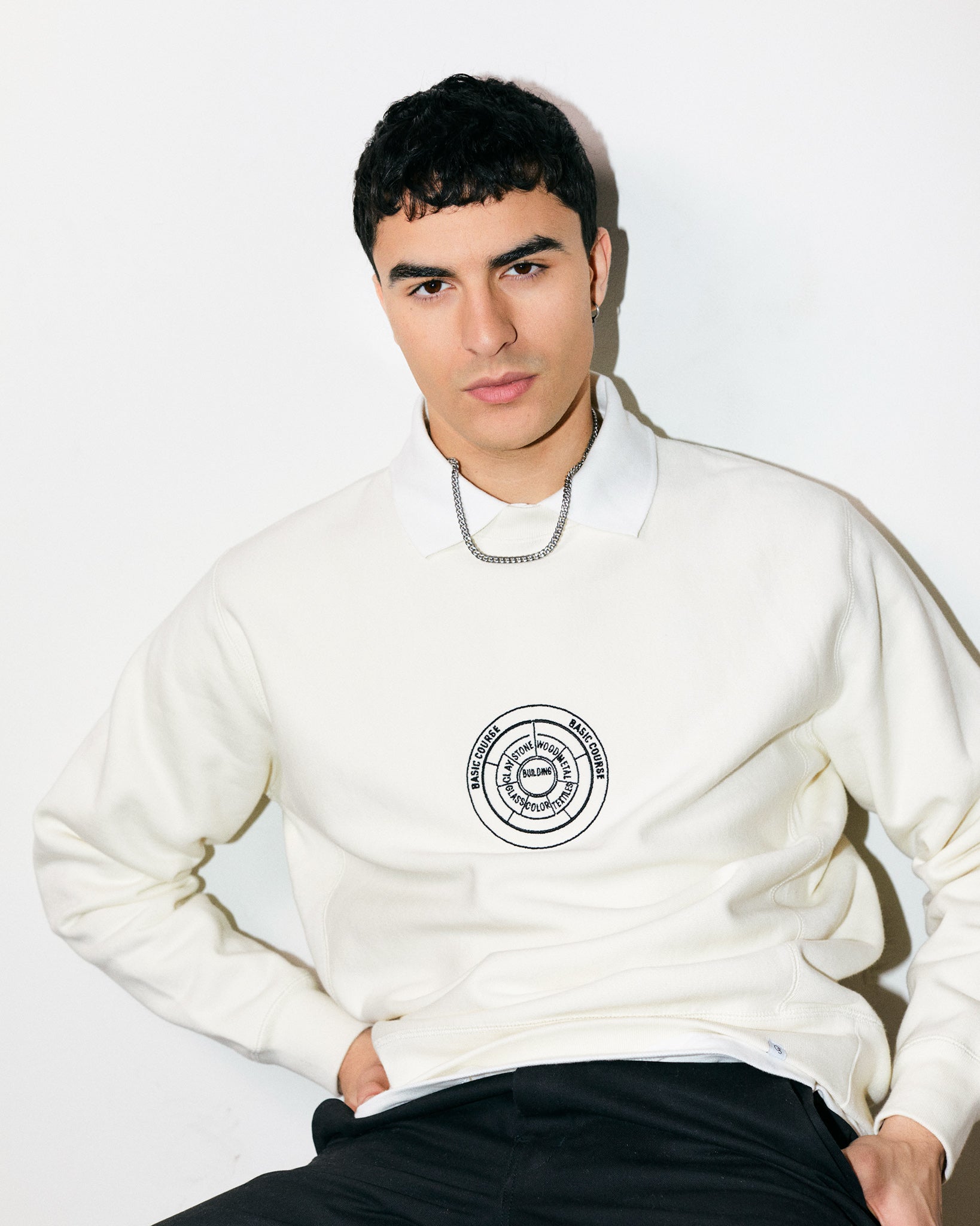 Arjang Mahdavi wears Cream / Off White / Ceramic Heavyweight Sweatshirt / Crewneck with embroidered print of the Bauhaus School Conceptual Curriculum Diagram and the Official Bauhaus seal on the back.